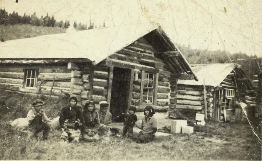 People In Front Of Log Houses